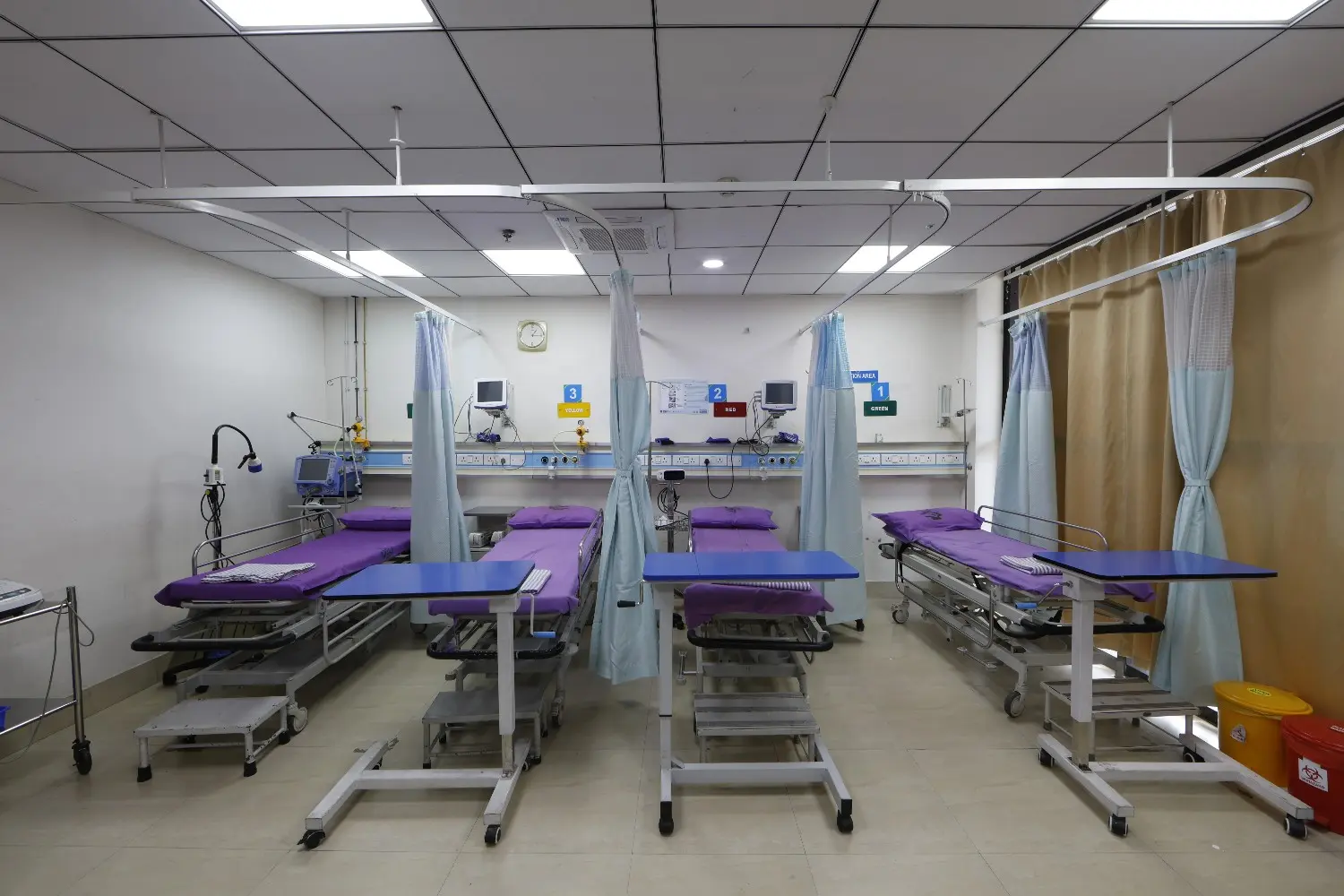 An empty emergency room ward at SMF Hospital in Mogappair with four beds separated by privacy curtains.