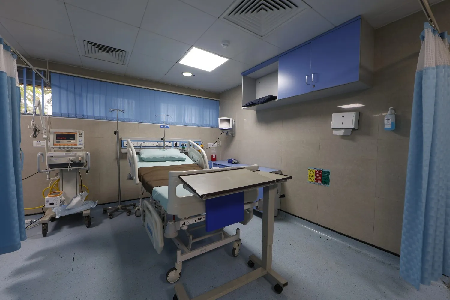 An empty ICU room with a patient bed and medical equipment.