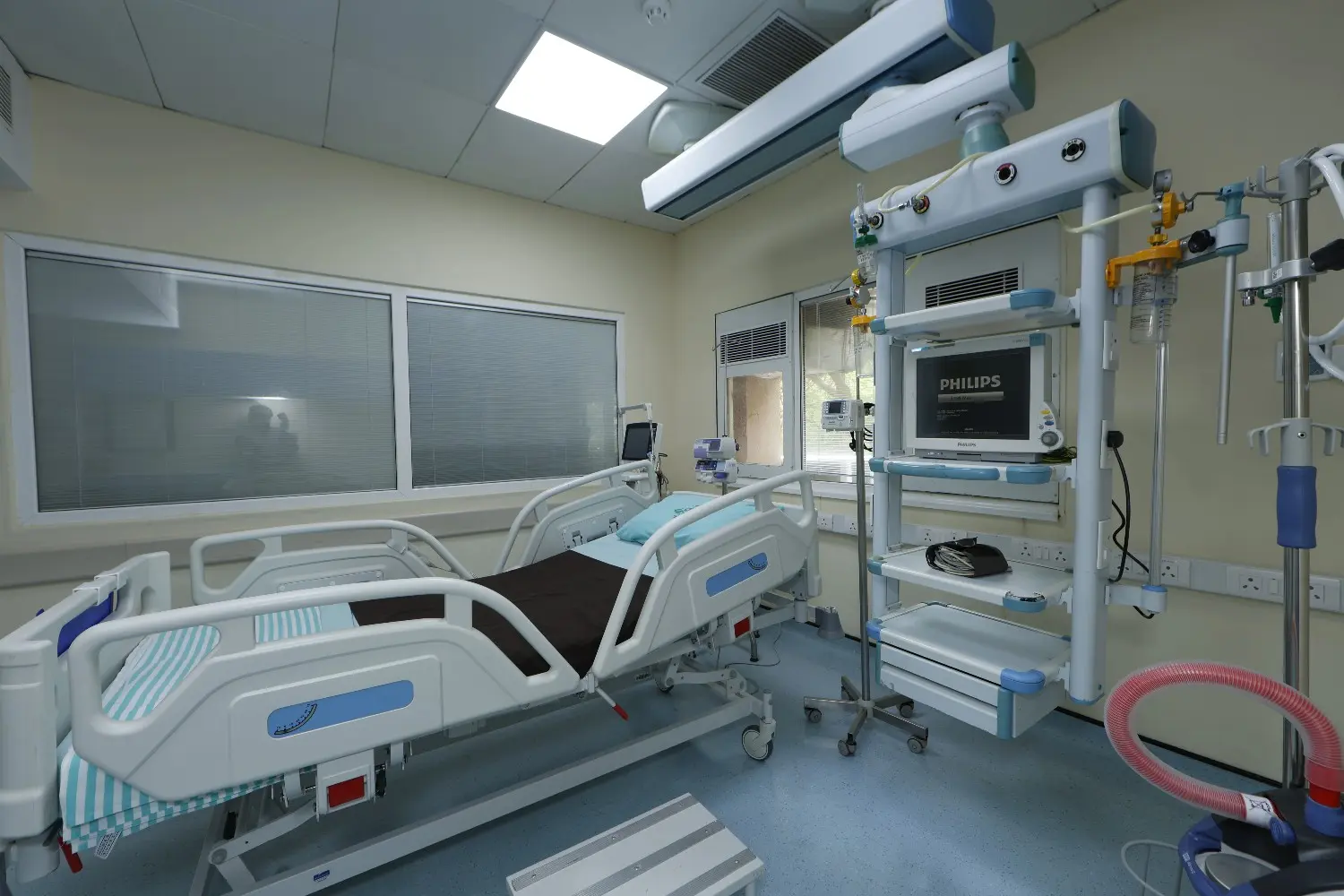 An empty intensive care unit (ICU) room featuring a modern hospital bed and a medical monitor tower.