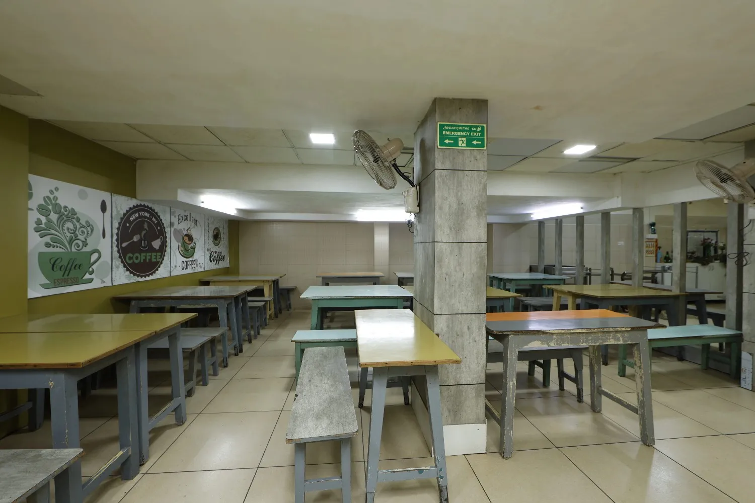 The empty dining area of the SMF Hospital canteen in Anna Nagar with wooden tables and benches.