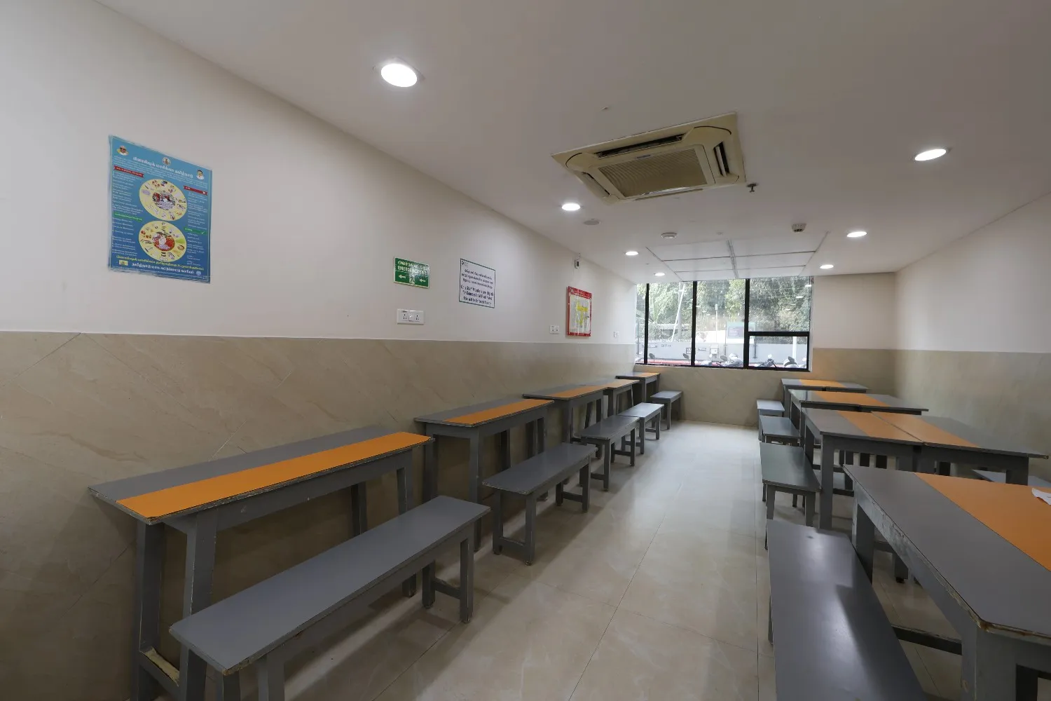 The empty dining area of the SMF Hospital canteen in Mogappair with tables and benches.