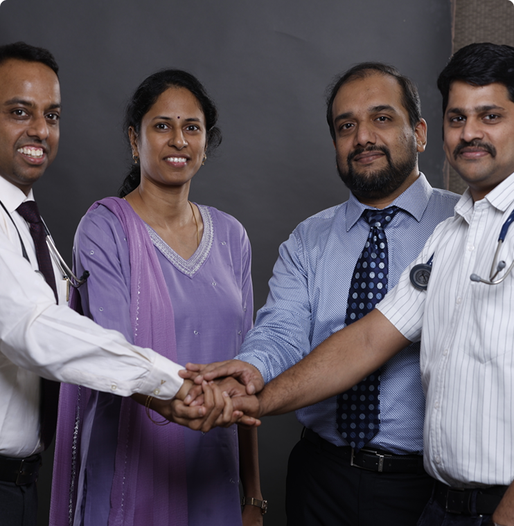 Four Doctors joining hands in teamwork gesture at hospital collaboration meet.